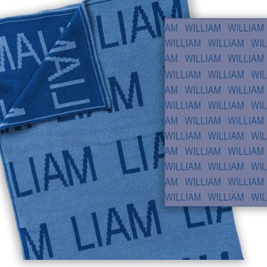 May include: A blue knitted baby blanket with the name "Liam" woven into the fabric. The blanket is reversible, with the name "Liam" on one side and the name "William" on the other side.