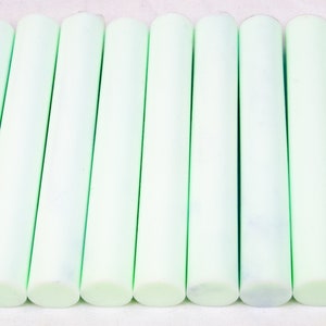 Może przedstawiać: Dwunastu jasnozielonych patyczków z polimerowej gliny, ułożonych w rzędzie na białym tle.