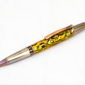 May include: A yellow and green patterned pen with a copper-toned clip and a silver metal body.