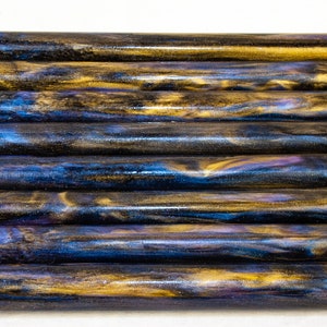 May include: A set of ten 1/2 inch diameter acrylic pen blanks with a swirling blue, gold, and purple pattern.