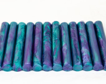May include: A row of 14 teal and purple wax sticks with a metallic sheen.