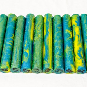 Könnte beinhalten: Eine Reihe von 12 grünen und gelben Acryl-Stiftrohlingen. Die Rohlinge sind etwa 12,7 cm lang und haben ein marmoriertes Muster.