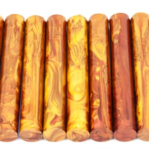 May include: Eight round acrylic pen blanks in a marbled pattern of gold and brown.