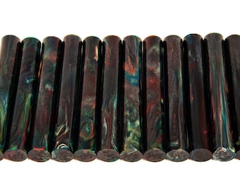 May include: A collection of twelve cylindrical, dark-colored objects with a marbled appearance. The colors include shades of green, blue, red, and brown. The objects are arranged horizontally against a white background.