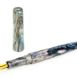 K&ouml;nnte beinhalten: Ein F&uuml;llfederhalter mit marmoriertem Design in Blau-, Grau- und Wei&szlig;t&ouml;nen, mit einer goldfarbenen Feder. Die Kappe ist abgenommen und neben den Stift gelegt. Der Stift befindet sich auf wei&szlig;em Hintergrund.