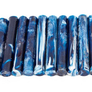 May include: A set of twelve blue and white marbled acrylic pen blanks. The blanks are approximately 5 inches long and have a swirling pattern of blue and white.