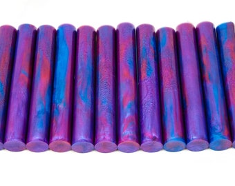 May include: A set of 12 purple and blue acrylic pen blanks with a metallic finish. The blanks have a swirling pattern of blue and red.