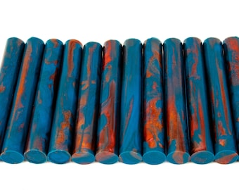May include: A collection of cylindrical objects with a teal and orange marbled pattern. The objects are arranged in a row against a white background. The objects appear to be made of a solid material.
