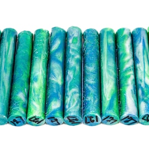 Puede incluir: Diez blancos de bolígrafo redondos de acrílico marmoleado en verde, azul y blanco. Cada blanco está etiquetado con un número.
