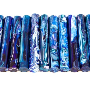 Puede incluir: Colección de objetos cilíndricos con un diseño azul y blanco veteado. Los objetos muestran una variedad de tonos azules, desde el índigo oscuro hasta el turquesa claro. Los extremos son de un azul oscuro sólido.