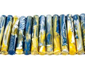 May include: A collection of cylindrical objects with a marbled appearance. The colors include shades of blue, yellow, and white, creating a swirling pattern. The objects are arranged in a row against a white background.