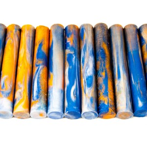 Puede incluir: Un juego de 12 blancos de bolígrafo de acrílico con un patrón de mármol azul, blanco y naranja.