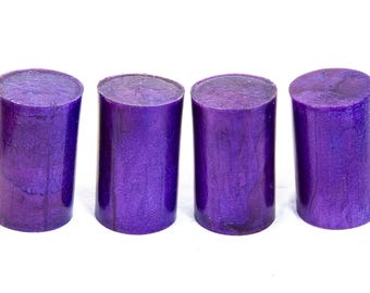 May include: Four cylindrical objects in a vibrant purple hue, arranged in a row. Each object has a flat top and bottom, with a slightly textured surface. The objects are evenly spaced against a white background.