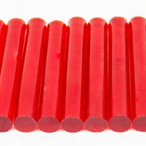 May include: Ten red translucent plastic rods, approximately 25 cm long, arranged in a row.