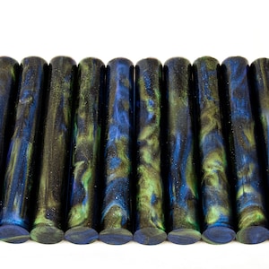 May include: A set of 15 black, blue, and green acrylic pen blanks with gold glitter. The blanks have a swirling, marbled pattern.