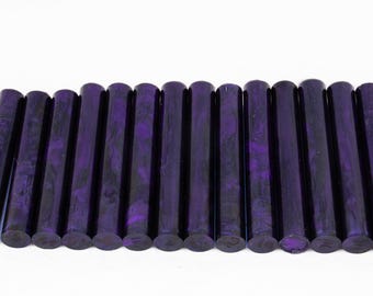 May include: A row of 18 purple and black marbled acrylic pen blanks. The blanks are round and have a smooth finish.