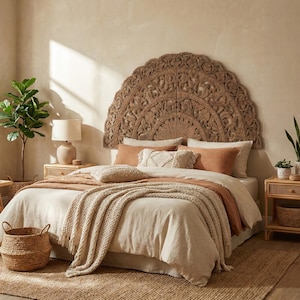 May include: A bedroom with a large, carved wooden headboard. The bed is dressed in neutral-toned bedding, including a beige duvet and terracotta-coloured pillows. A woven throw and a jute rug add texture. A lamp and plants complete the scene.