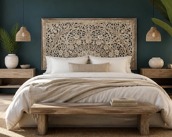 May include: A bedroom featuring a large, rectangular, intricately carved wooden headboard with a floral pattern, positioned against a dark teal wall. The bed is dressed in white linens with a beige throw, flanked by two wooden nightstands and pendant lights.