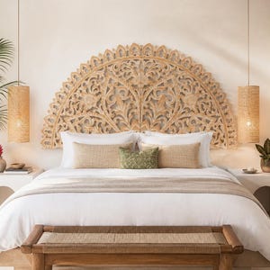 Puede incluir: Un gran cabecero de madera tallada en forma de semicírculo con intrincados motivos florales sobre una cama. La cama cuenta con ropa de cama blanca, dos almohadas rectangulares beige y un pequeño cojín verde, con un banco de madera a los pies.