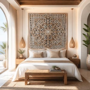 May include: A large square wooden wall panel featuring an intricate carved floral mandala design in shades of brown and cream, mounted above a bed with white linens, two woven pendant lights, and a wooden bench at the foot of the bed.