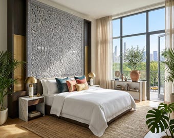 May include: A bedroom featuring a large, rectangular, gray carved wood wall panel with intricate floral patterns mounted behind a bed. The bed has white bedding, two teal pillows, one orange pillow, and one gold pillow, flanked by two marble nightstands.