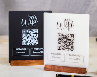 May include: Two WiFi signs, one black and one white, with wooden bases. Each sign displays a QR code, the word "Wifi", and network and password information. The signs are on a marble surface.