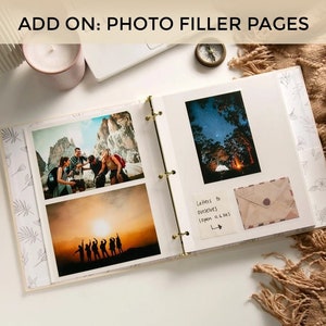 May include: A white photo album with a gold binder ring. The album is open to two pages, each with a photo of a group of people. The left page has a photo of people in a mountainous landscape, and the right page has a photo of people camping under a starry sky. The album has a decorative border with a floral pattern.