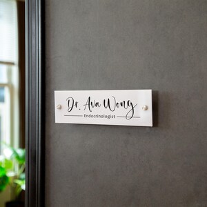 May include: White rectangular sign with black text that reads "Dr. Ava Wong - Endocrinologist".