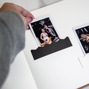 Puede incluir: Un &aacute;lbum de fotos blanco con dos fotos en blanco y negro insertadas. Las fotos son de una pareja y una mano sosteniendo un anillo.