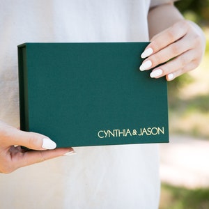 May include: A green gift box with gold lettering that reads "CYNTHIA & JASON".