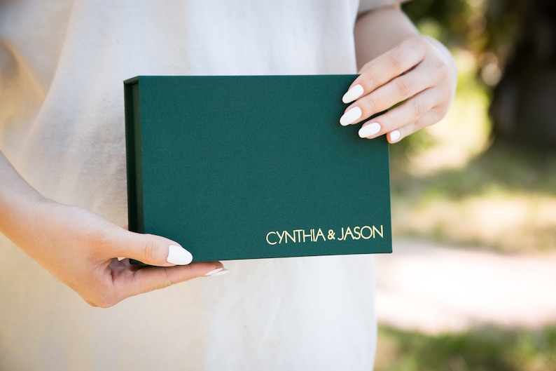 May include: A green gift box with gold lettering that reads "CYNTHIA & JASON".