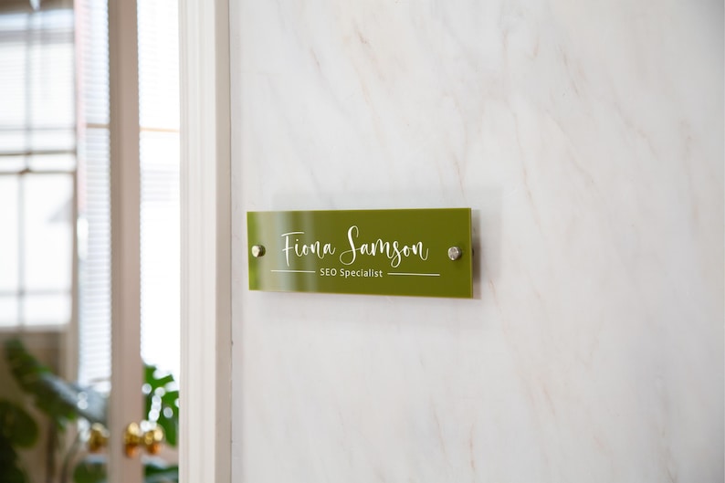 May include: A green office door sign with white text that reads "Fiona Samson, SEO Specialist".
