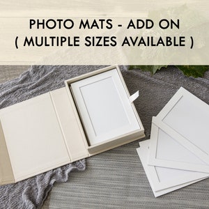 May include: A set of white photo mats in various sizes, displayed in a beige box with a lid. The mats are designed to fit photos and create a professional look for framing.