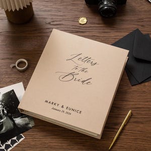 May include: A beige wedding keepsake book titled "Letters to the Bride" with the names Marky & Eunice and the date January 29, 2026. The book is on a wooden surface with a pen, photos, and black envelopes.
