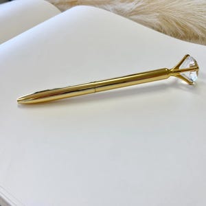 May include: A gold pen with a clear diamond-shaped top.