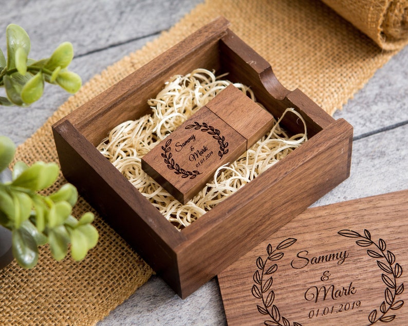 May include: A wooden box with a USB drive inside. The box and drive are engraved with the text "Sammy & Mark 01.01.2019" and a wreath design.