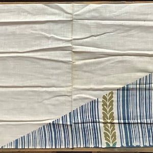 May include: A white fabric panel with a diagonal pattern of blue, purple, and gold stripes and leaf shapes. The pattern is on the right side of the panel, with the left side being plain white.