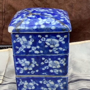May include: A blue and white porcelain box with a floral design. The box is made up of four stacked pieces.