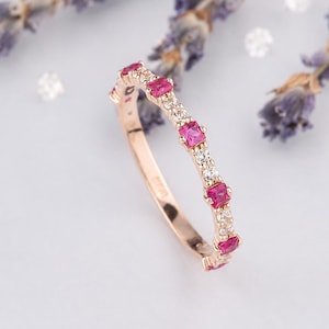 Könnte beinhalten: Ein Ring aus Roségold mit einem abwechselnden Muster aus quadratisch geschliffenen, leuchtend pinken Edelsteinen und kleinen, runden, klaren weißen Steinen. Das Metallband ist poliert und die Steine sind entlang der oberen Ringhälfte eingefasst.
