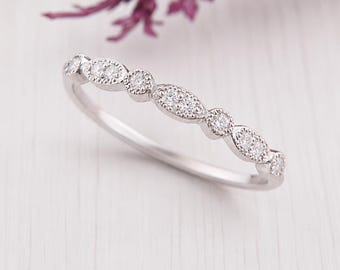 May include: A silver-toned band ring featuring a series of alternating round and marquise-shaped settings, each encrusted with small clear stones. The metal surface has a polished finish, and the design includes delicate milgrain detailing.