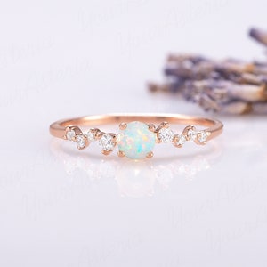 May include: A delicate rose gold ring with a white opal gemstone and small diamonds set in a delicate, scattered pattern.