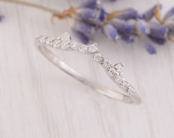 May include: A delicate silver ring with a curved design and small, sparkling diamonds.