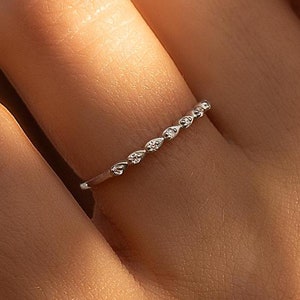 May include: A delicate silver ring with a row of small, round diamonds set in a curved pattern.