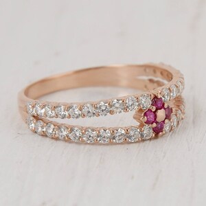 Puede incluir: Un anillo de oro rosa con una doble banda de peque&ntilde;as piedras transparentes y un grupo central de piedras rosas.
