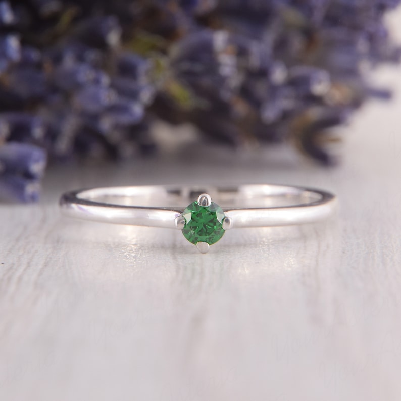 May include: A simple silver band ring with a single green gemstone in the center.