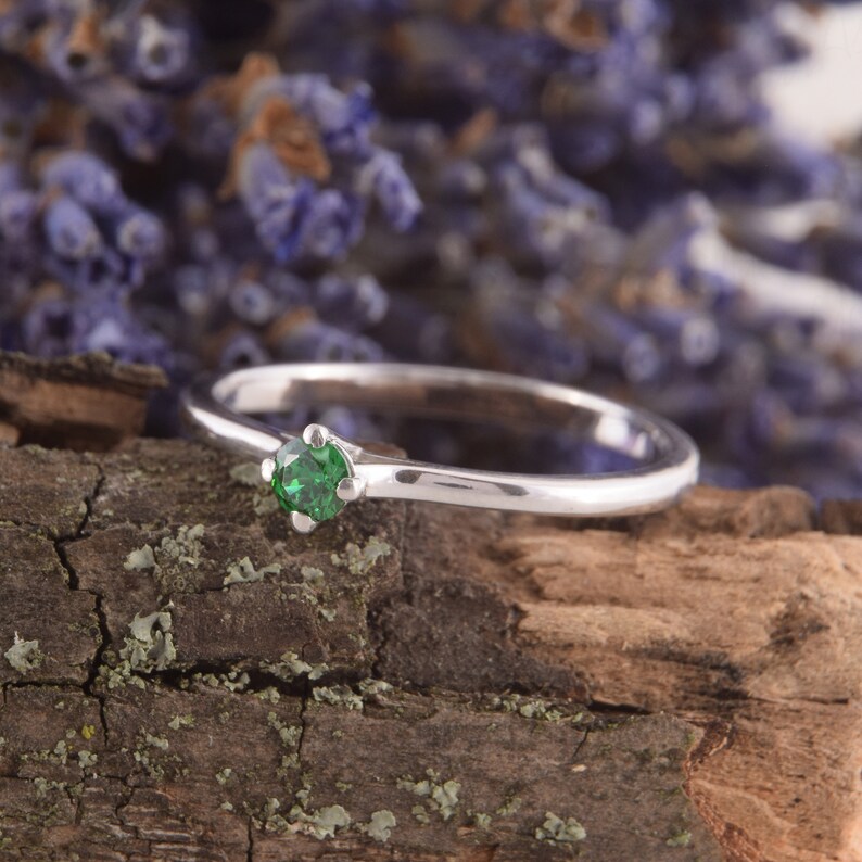 May include: A silver ring with a single green gemstone set in the center.