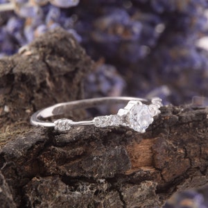 May include: A silver ring with a single large clear stone and smaller stones set in a delicate band.