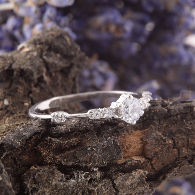 May include: A silver ring with a single large clear stone and smaller stones set in a delicate band.