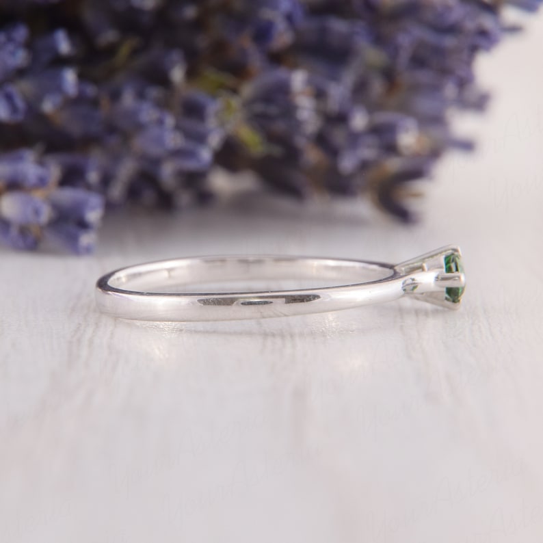 May include: A silver ring with a single green gemstone set in a prong setting.