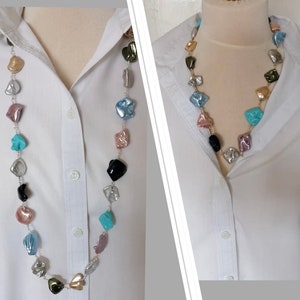 May include: A long necklace with a silver chain and colourful, irregular shaped beads. The beads are in shades of turquoise, pink, gold, black, and silver.
